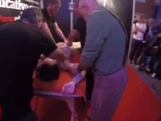 Um grupo de pessoas massagem este jovem e tattoed adolescente em o mesmo tempo em público